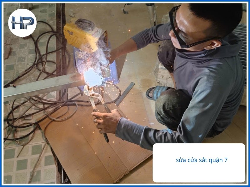 Hình ảnh thợ sửa cửa sắt Quận 7 đang hàn và gia cố bản lề cửa sắt tại nhà khách hàng, xử lý cửa bị kẹt và xệ nhanh chóng.