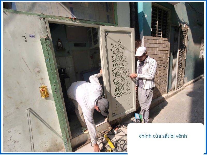 Thợ cơ khí lưu động đang tiến hành nắn chỉnh cửa sắt bị vênh ngoài trời.