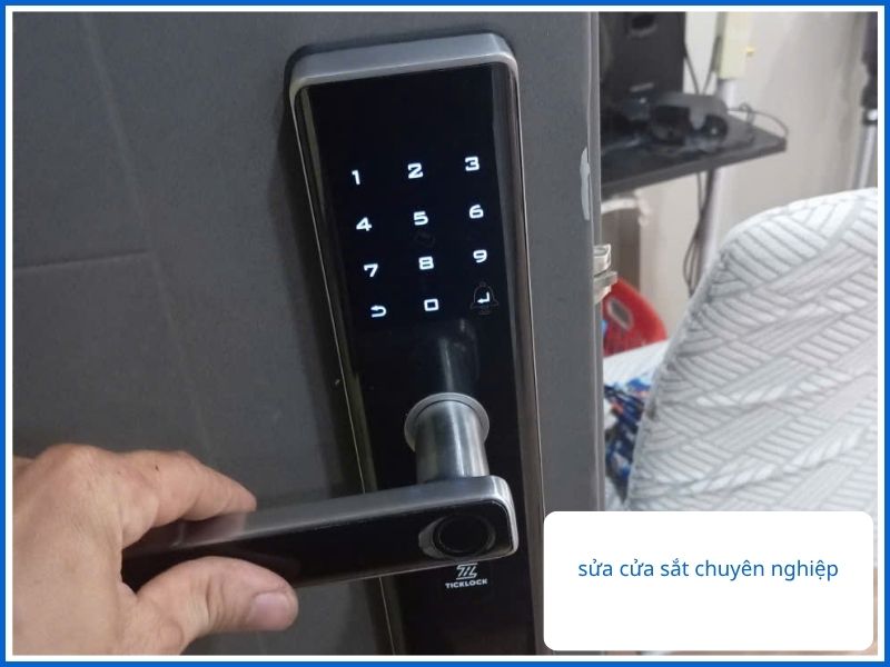 Tay người dùng đang gạt thử tay nắm của ổ khóa điện tử thông minh màu đen trên đố cửa sắt