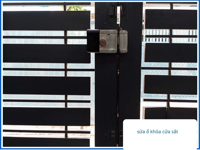 Thợ đang xử lý sửa ổ khóa cửa sắt cổng hộp màu đen bị kẹt cho khách hàng tại TPHCM