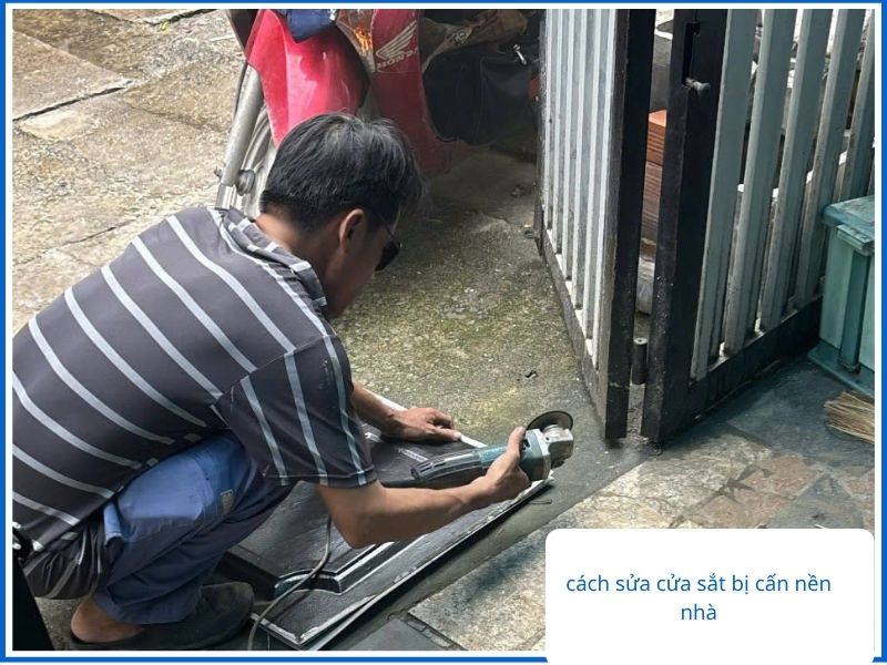 Thợ cơ khí dùng máy mài xử lý cửa sắt bị cấn nền nhà.