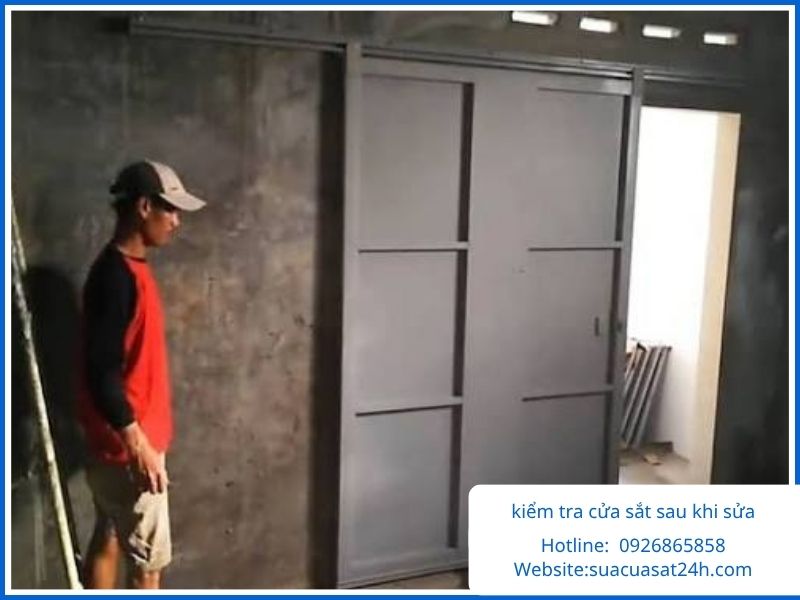 Kỹ thuật viên kiểm tra cửa sắt lùa sau khi sửa chữa xong